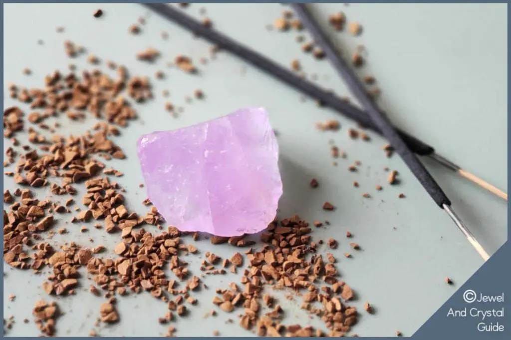 Photo of purple amethyst crystal lying next to incense sticks and sand granules