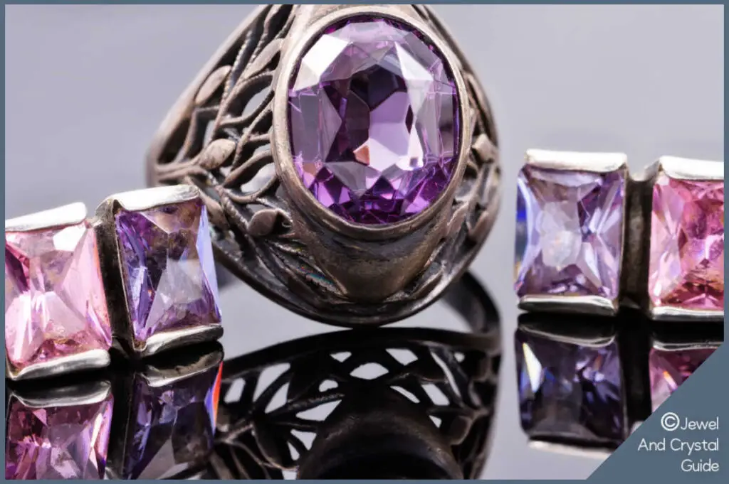 Photo of purple and pink amethyst ring and earrings lying next to each other on a reflective surface